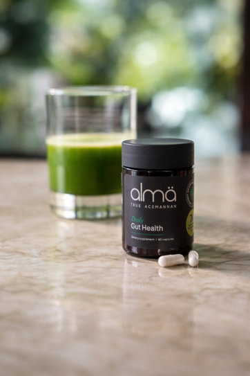 almä Daily Gut Health black jar beside aloe drink