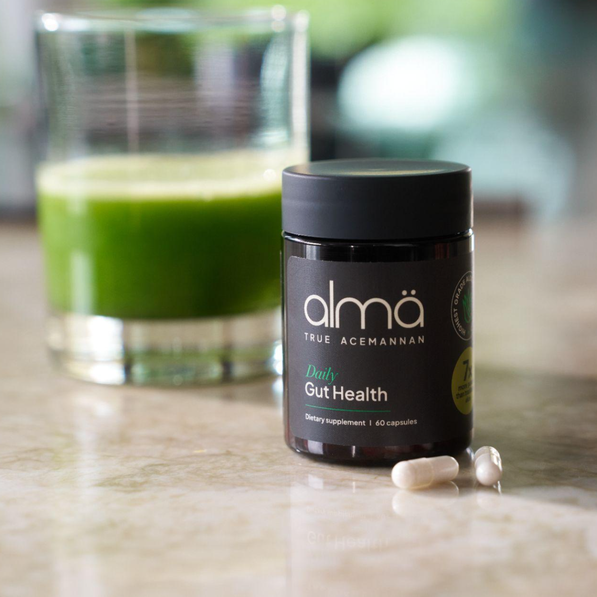 almä Gut Health jar beside a glass of green aloe juice with two capsules